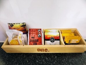 A wooden box containing various food items including chocolate, tea, and sugar packets.
