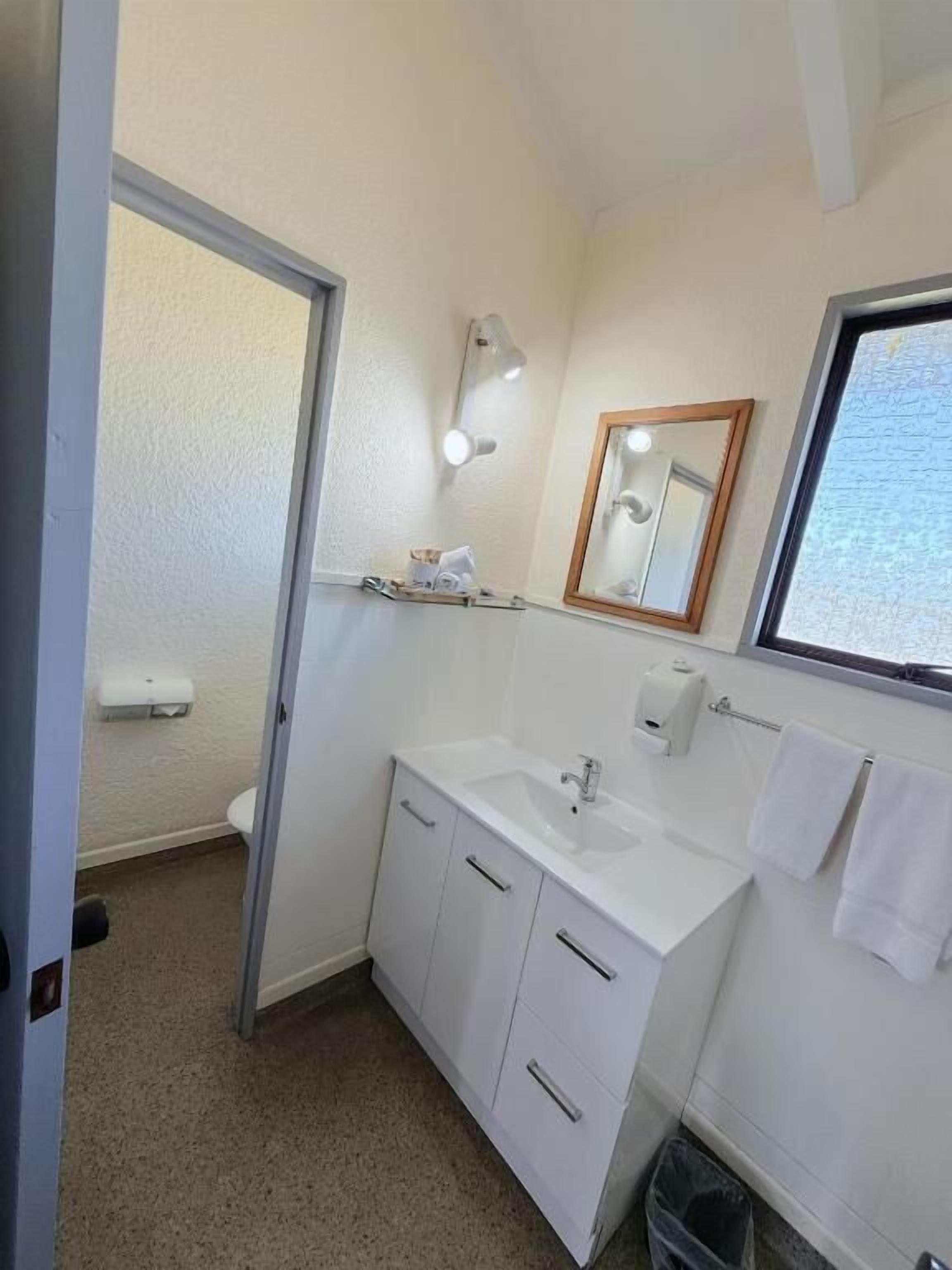 A small, clean bathroom with a sink, mirror, and towel rack.