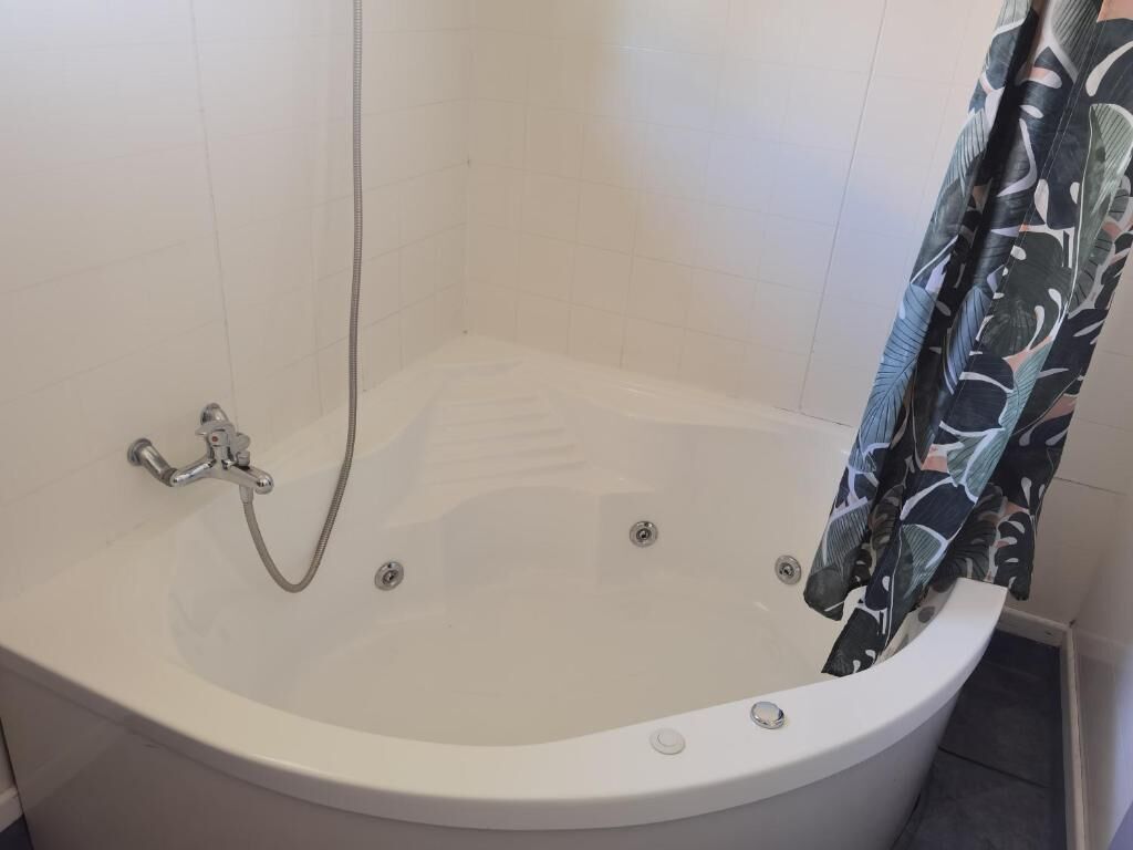 Eine weiße Badewanne mit Duschkopf und Vorhang.