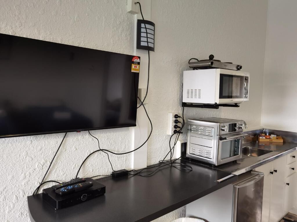 A kitchenette with a flat-screen TV mounted on the wall, a microwave, and a toaster oven on the counter.
