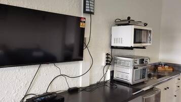 A kitchenette with a flat-screen TV mounted on the wall, a microwave, and a toaster oven on the counter.