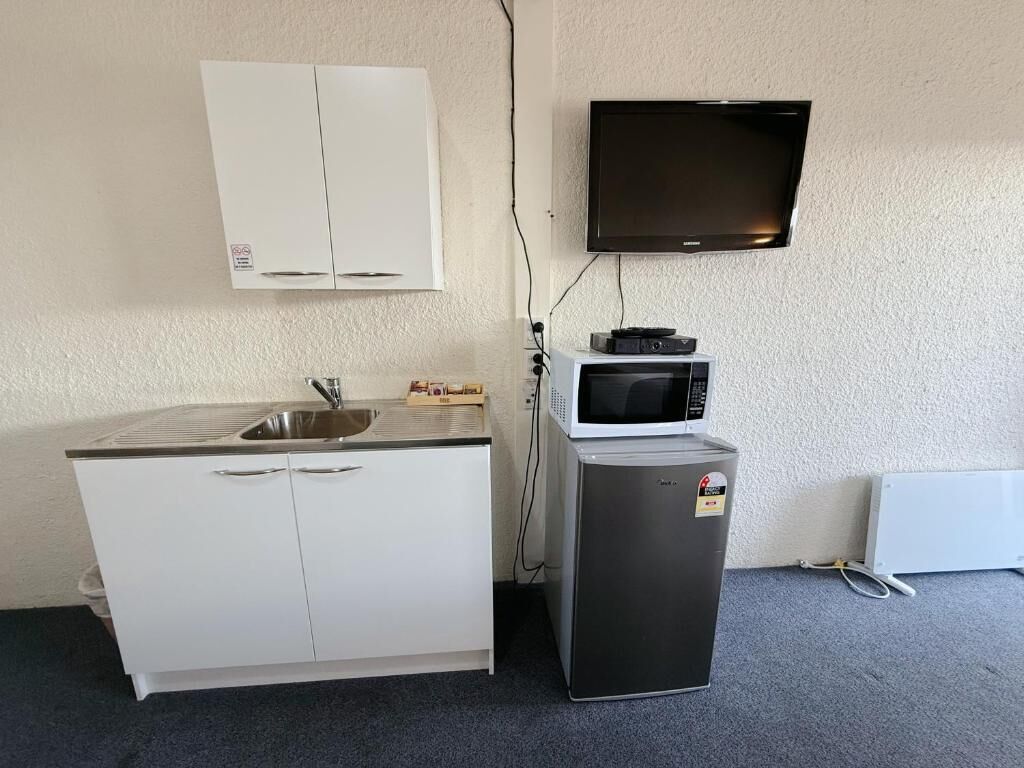 Pieni, käytännöllinen keittiönurkkaus, jossa on pesuallas, mikroaaltouuni ja pieni jääkaappi.