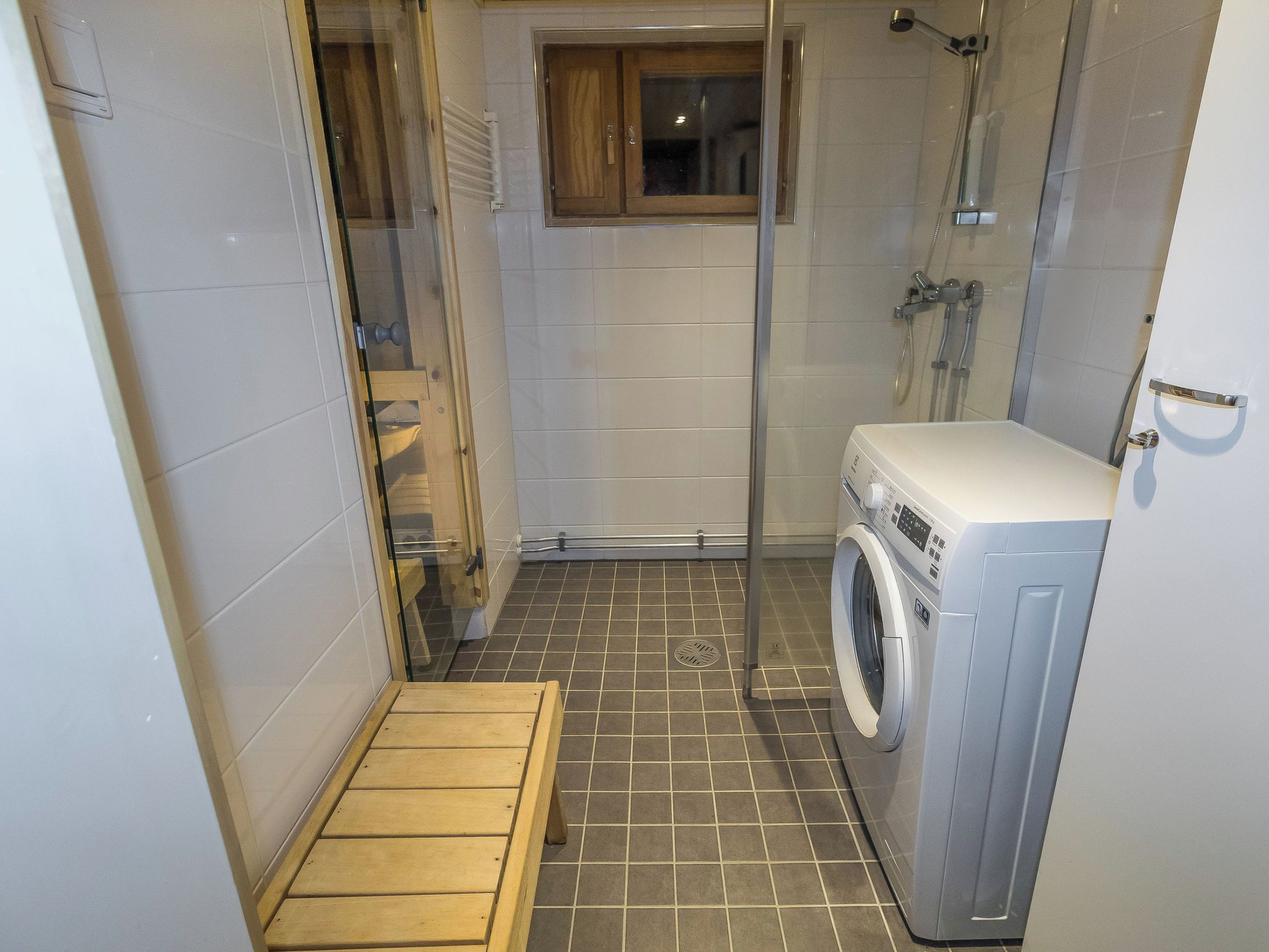 Ein kleines Badezimmer mit Dusche, Toilette und Waschmaschine.