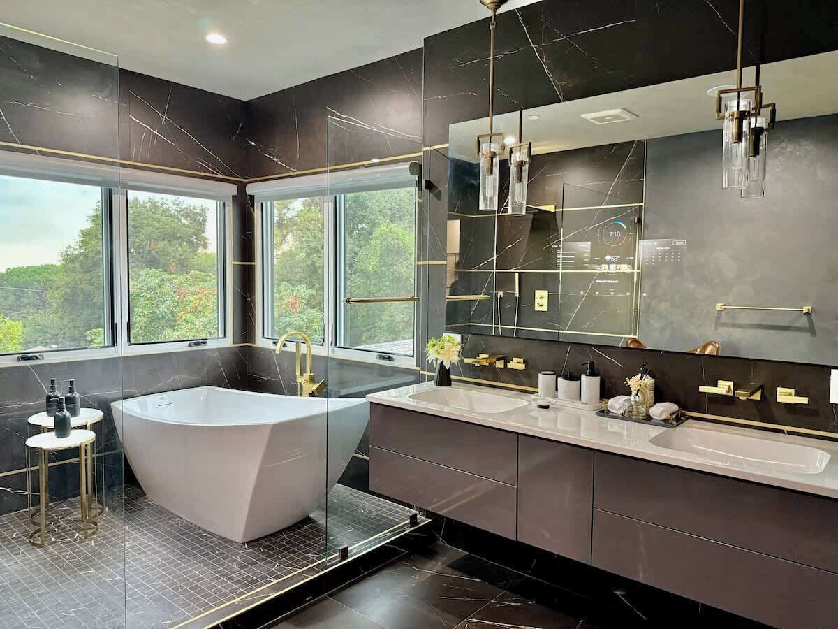A modern bathroom with a freestanding bathtub, a large mirror, and a window providing a view of greenery.