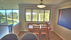 A dining area with a large window, wooden table, and chairs.