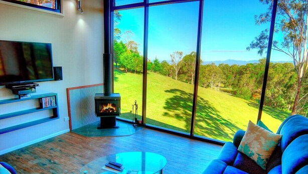 A modern living room with a television, a glass coffee table, and a sofa with floral cushions.