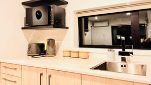 Una cocina moderna con microondas integrado, cafetera y un ventanal sobre el fregadero.