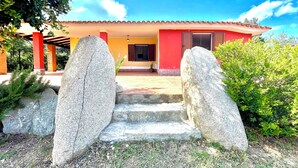 Una casa con facciata rossa, un patio piastrellato e una scalinata in pietra che conduce all'ingresso.
