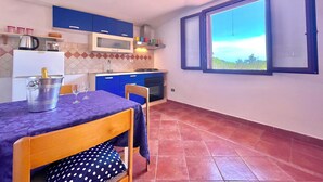 Una cucina compatta con mobili blu, uno schienale piastrellato e una finestra con vista.