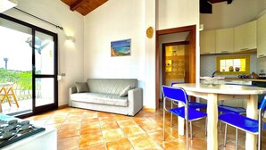 Una sala acogedora con un sofá, una mesa de comedor con sillas y una cocina visible a través de una puerta abierta.