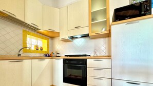 Una cocina moderna con armarios blancos, un horno negro, un microondas y un lavamanos.