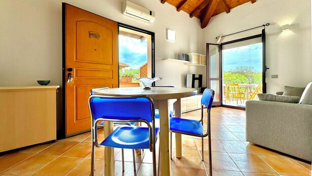Una habitación acogedora con techo de madera, una mesa de comedor con sillas, un sofá y un televisor.