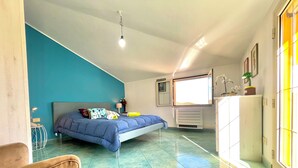 A bedroom with a bed, a nightstand, a chair, a radiator, and a window with a view.