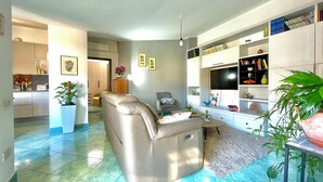A modern living room with a leather sofa, a dining area with a table, and a kitchen in the background.