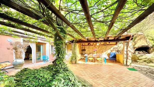 Un patio cubierto con pared de piedra, una mesa con sillas y un horno de piedra.