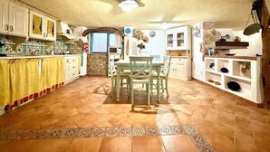 Una cocina amplia con comedor, pared de piedra y piso de baldosas.