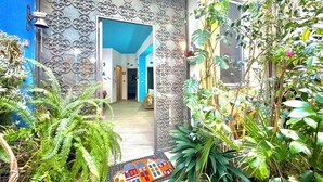 A house with a decorative metal gate, a wooden door, and a colorful mat at the entrance. - "  La  Corte   Azzurra  " (Bari Sardo)