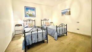 A room with two beds, a small table, and a chair. - "  La  Corte   Azzurra  " (Bari Sardo)