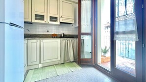 Uma cozinha com armários brancos, uma pia de aço inoxidável e uma janela com vista para o exterior.