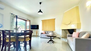 Uma sala de estar moderna com área de jantar, sofá, lareira e televisão na parede.