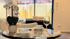 A dining table set with plates, bowls, and cutlery, accompanied by a wine glass. - Heartstay Studio CBD, CHC (Christchurch)