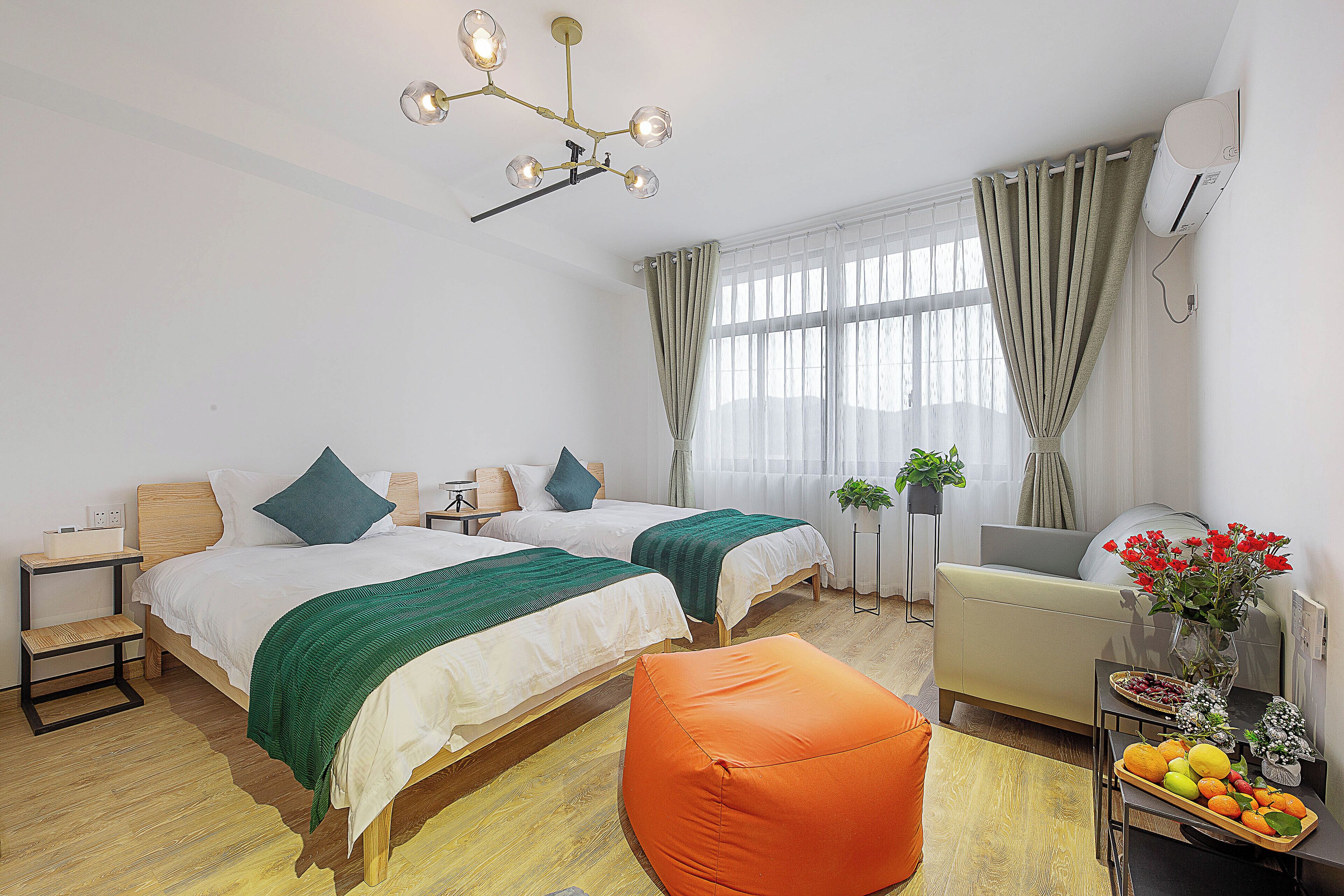 Una habitación de hotel moderna con dos camas, un sofá, una mesa de comedor con fruta y una planta.