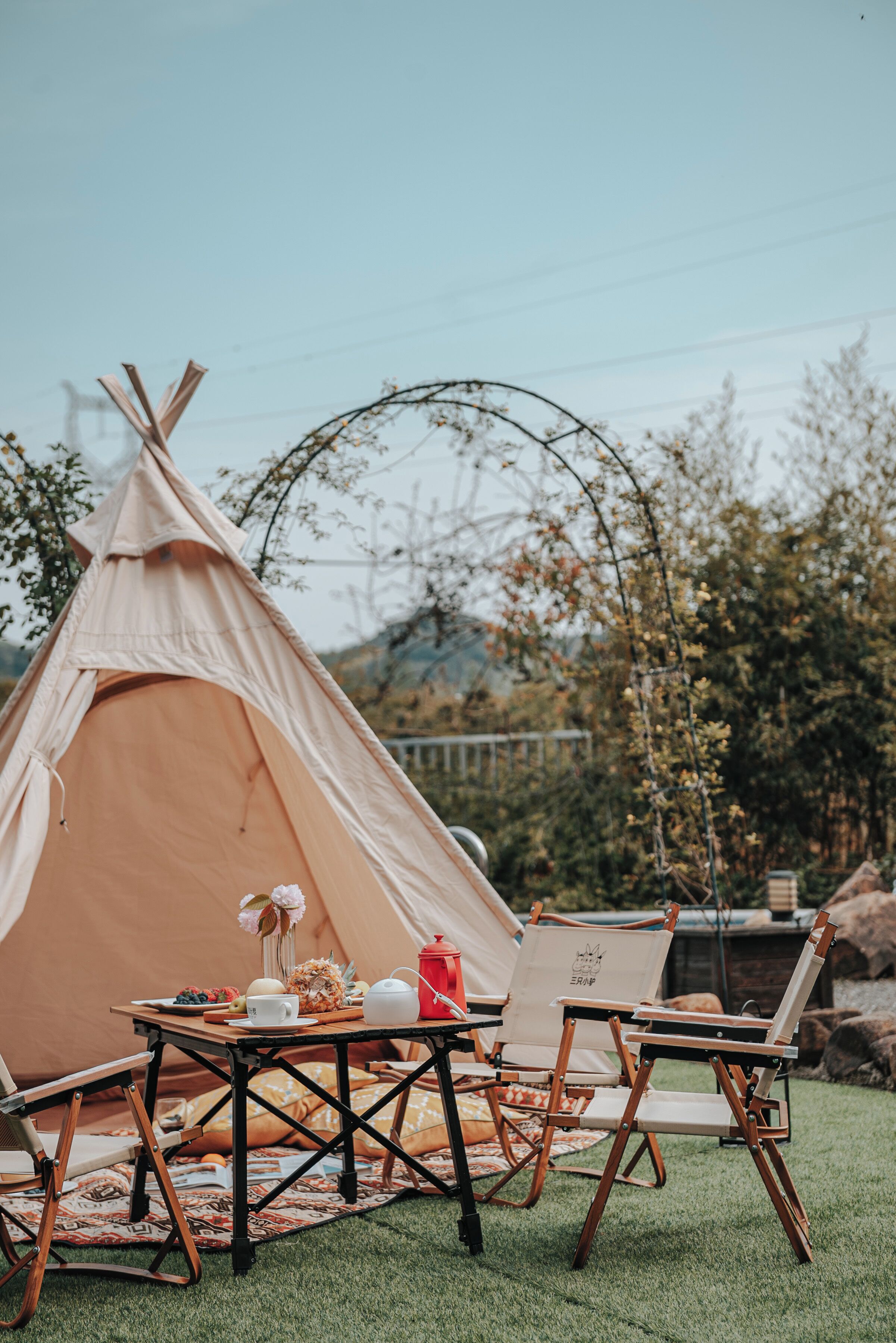 A tent with a table set for a meal, surrounded by camping chairs.