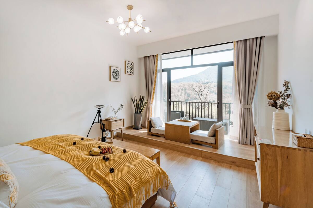 A modern bedroom with a large bed, a balcony with a view, and a dining area.