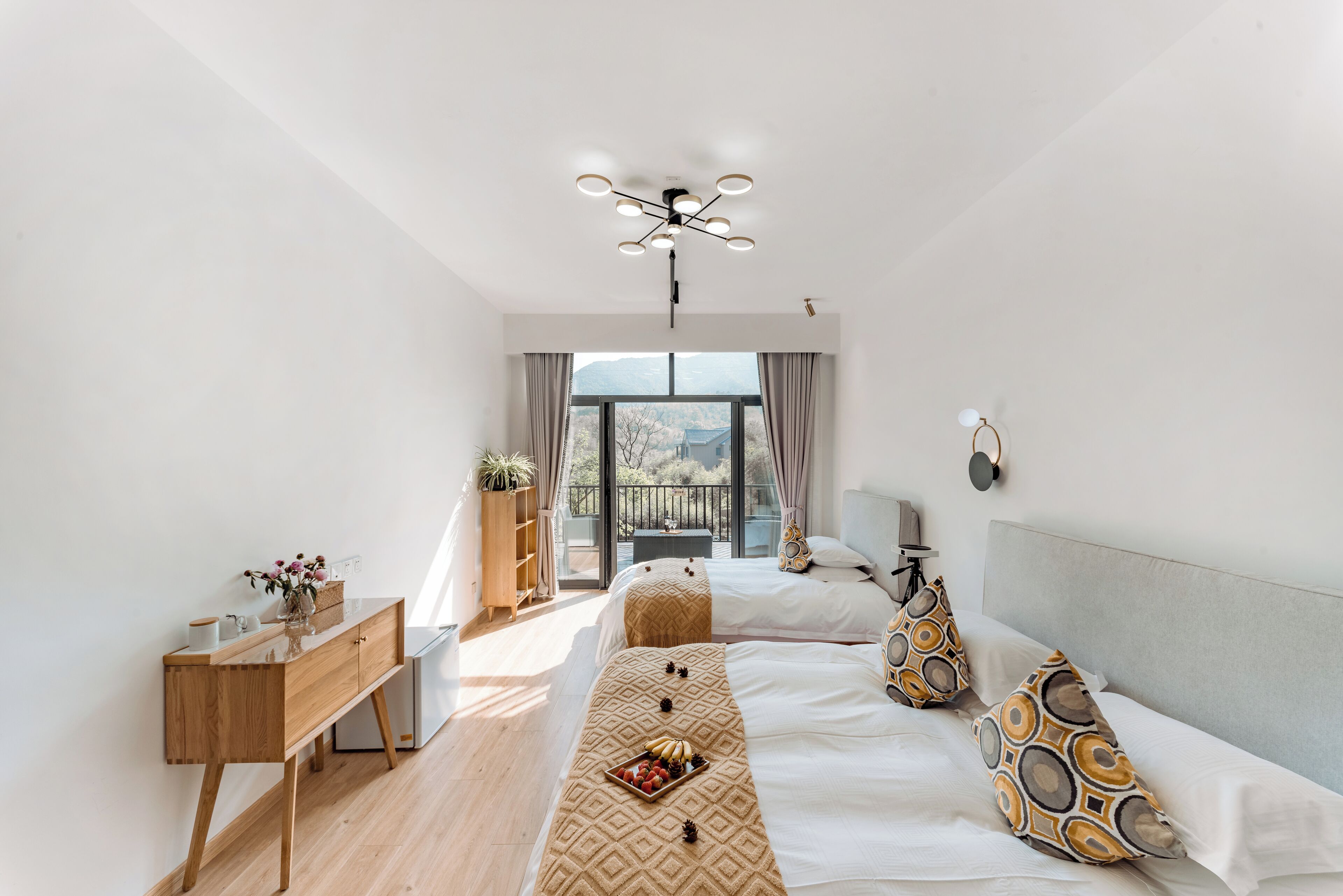 A modern bedroom with a large bed, bedside tables, a dresser, and a view of the outdoors.