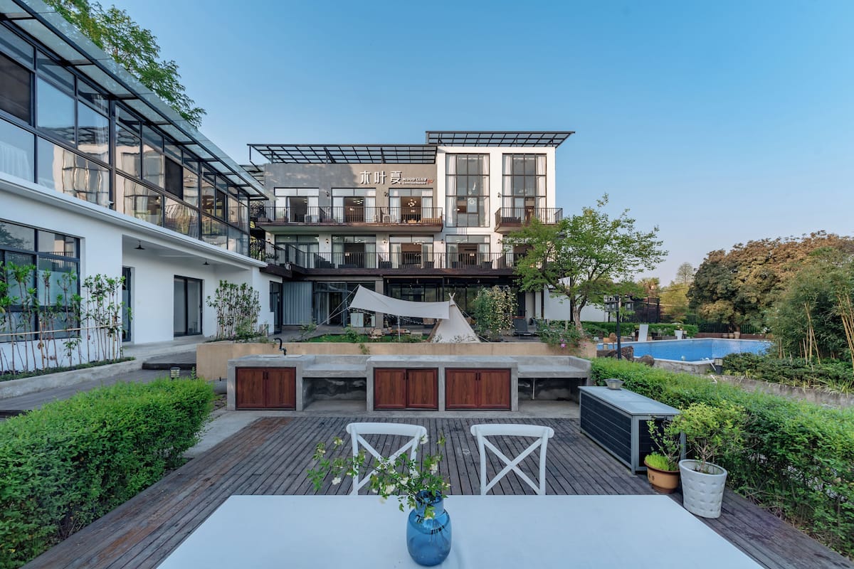 A modern building with a rooftop patio, outdoor seating, and a swimming pool.