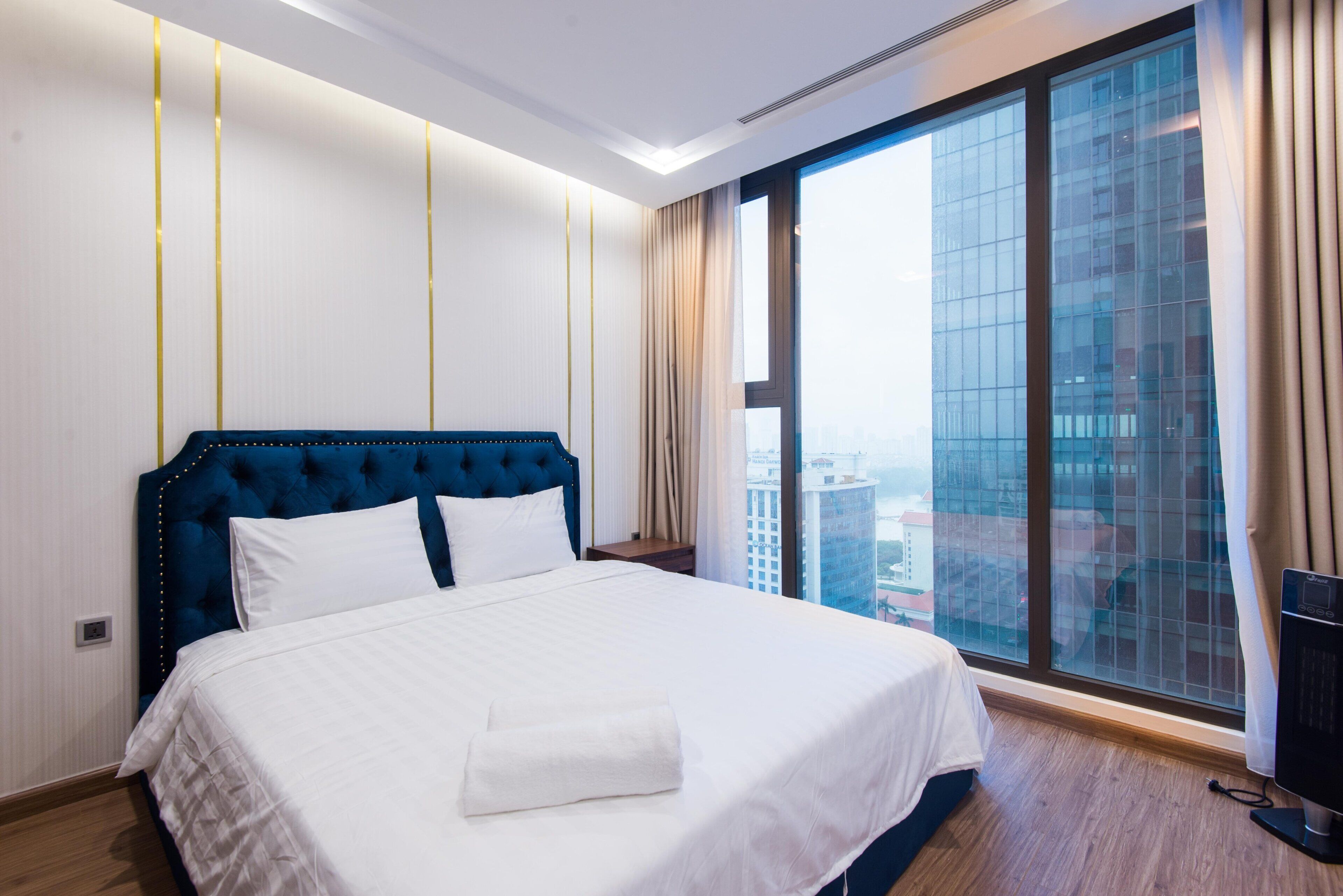 Une chambre d’hôtel dotée d’un grand lit, offrant une vue sur le paysage urbain grâce à une grande fenêtre, et présentant un design moderne.