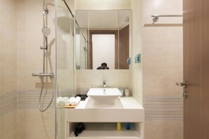 A modern bathroom with a glass-enclosed shower, a white sink, and a mirror.