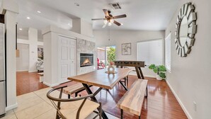 A modern kitchen with a built-in oven, a dining area with a wooden table and chairs, and a ceiling fan. - @marbella Lane - 4BR Lavish Castle Retreat (Indio)