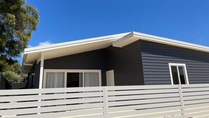 A modern single-story house with a dark exterior, white exterior trim, and a covered porch. - The Front House (Augusta)