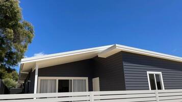 A modern single-story house with a dark exterior, white exterior trim, and a covered porch.