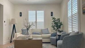 A living room with a sofa, armchairs, a coffee table, and a floor lamp. - Cozy Retreat Near Downtown Perfect for Families (Long Beach)