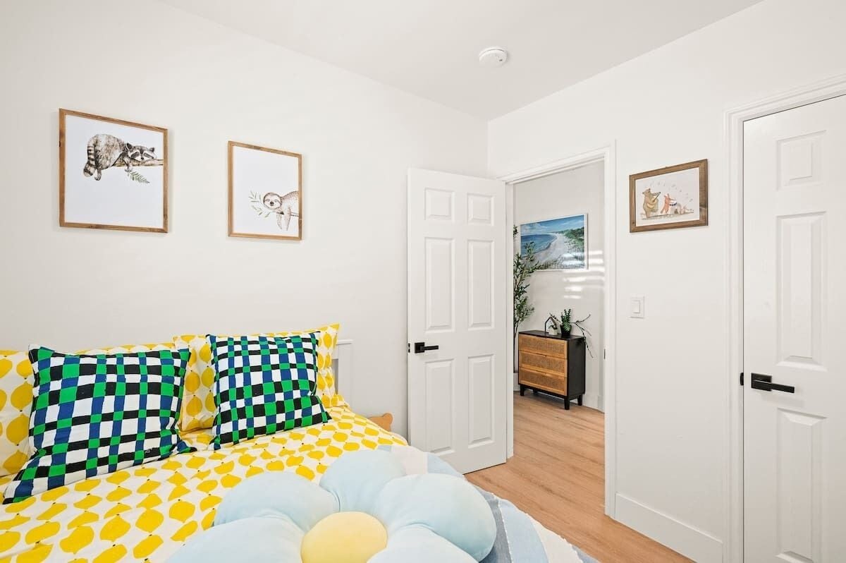 A bedroom with a bed, pillows, and two framed pictures on the wall.