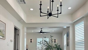A dining room with a round table, six chairs, a chandelier, and a ceiling fan. - Cozy Retreat Near Downtown Perfect for Families (Long Beach)