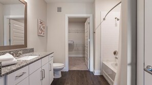 Un baño moderno con lavamanos de granito, inodoro y ducha a ras de suelo con puerta de vidrio.