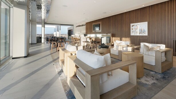 Un intérieur moderne avec un espace salon comprenant des canapés et des fauteuils, un mur d’accent en bois et une vue dégagée grâce à de grandes fenêtres.