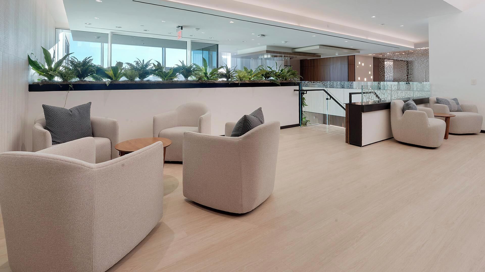 A modern lobby with sofas, a reception desk, and a glass railing.