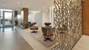 Un intérieur moderne comprenant un espace salon, un élément de séparation décoratif et une vue dégagée grâce à de grandes fenêtres.