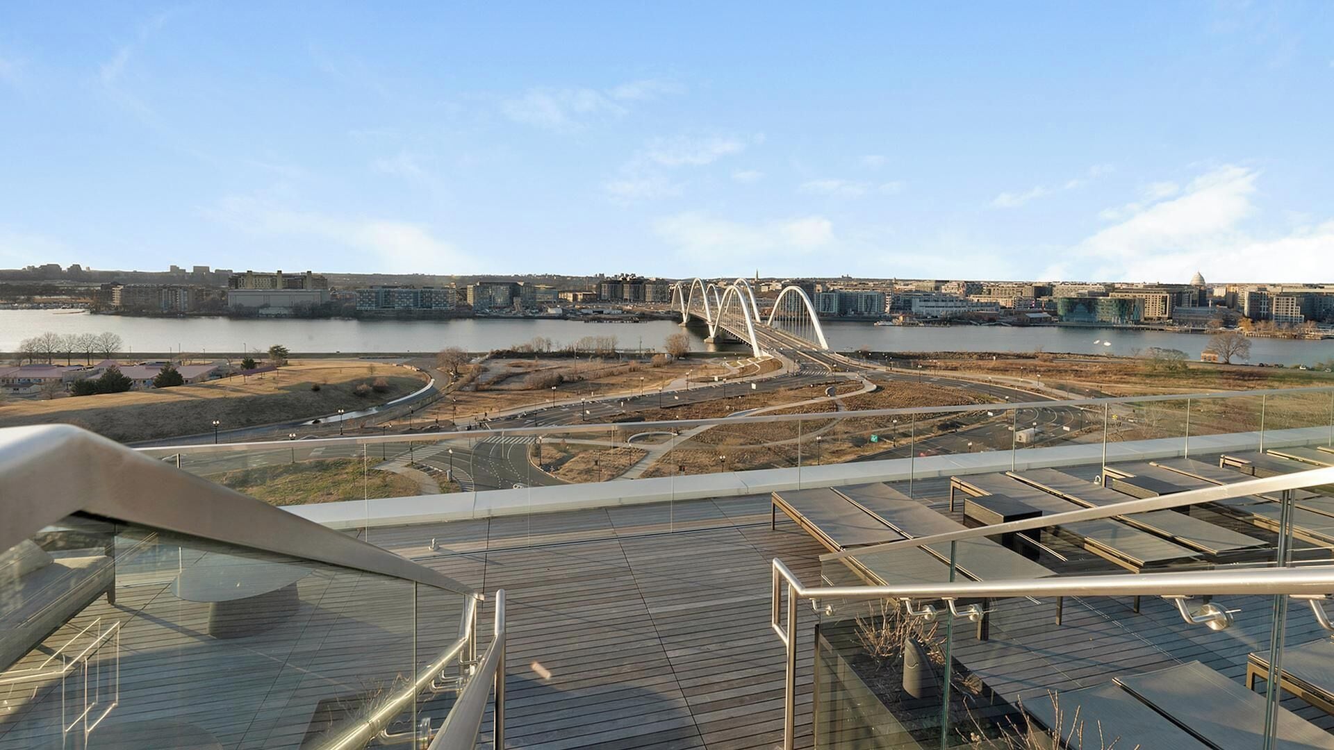 Een modern gebouw met een glazen gevel, met zicht op een rivier en een brug op de achtergrond.