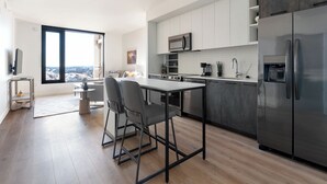 Una cocina moderna con una isla grande, electrodomésticos de acero inoxidable y vistas a través de un ventanal.