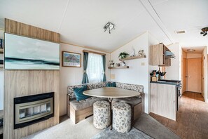 A compact living space with a sofa, a round table, a fireplace, and a kitchen area. - 3 Bed-Sleeps 8-Pet Friendly-Parking-Sea View (Exmouth)