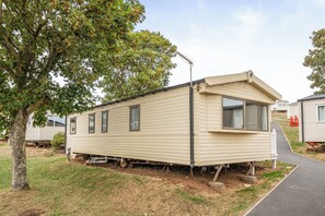 A mobile home with a single window and a small porch area. - 3 Bed-Sleeps 8-Pet Friendly-Parking-Sea View (Exmouth)