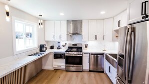 A modern kitchen with white cabinets, stainless steel appliances, and a wooden countertop.