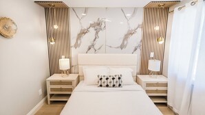 A modern bedroom with a large bed, two bedside tables with lamps, a marble wall, and vertical wooden slats.