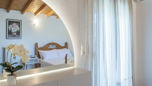 Ein Schlafzimmer mit einem hölzernen Kopfende, einem Nachttisch mit Tasse und Untertasse sowie einem Spiegel, der den Raum widerspiegelt.