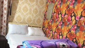 Uma cama com lençóis brancos, parede com padrão floral e cortina estampada.